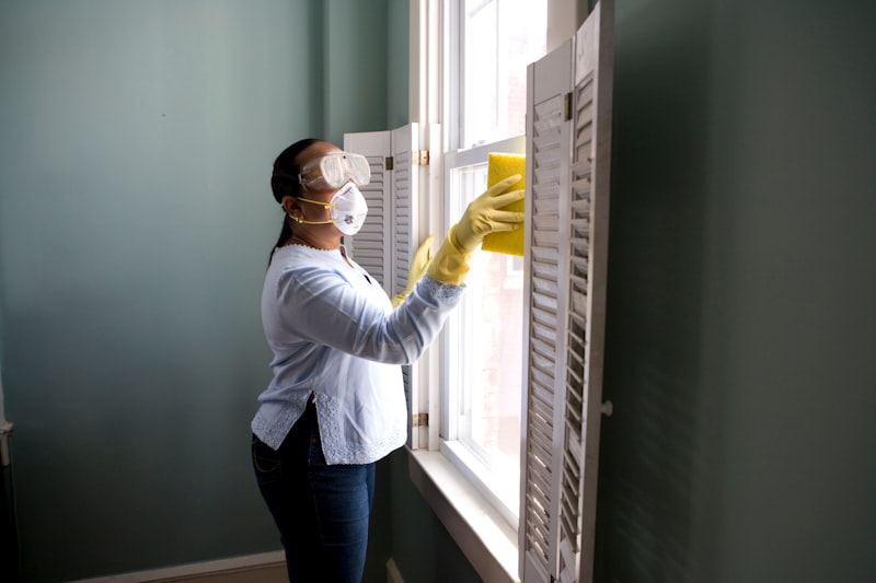 Professional cleaner in uniform wiping down a surface in a modern office environment